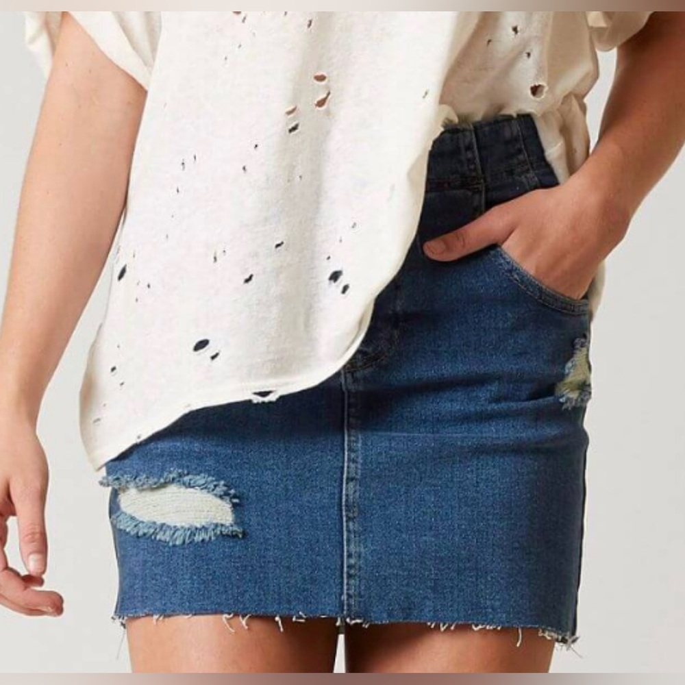 Free People distressed denim mini skirt with a buckle back and raw hem.